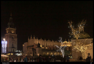 Illuminated christmas tree against buildings in city at night