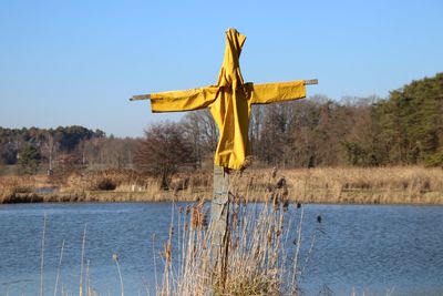 Scarecrow on lake against clear sky