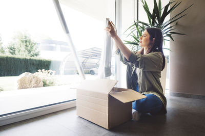 Rear view of woman using digital tablet while sitting at home