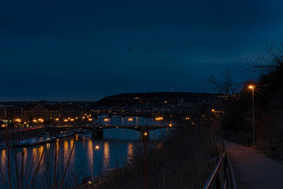 Illuminated bridge over river against sky in city at night