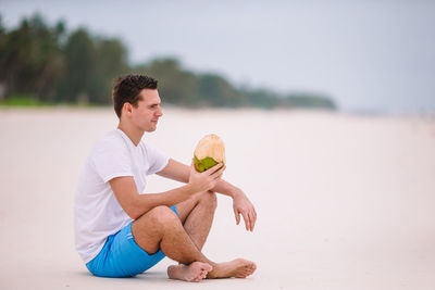 Side view of boy playing with ball at beach