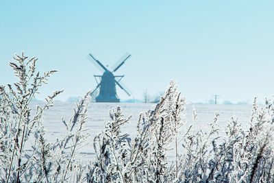 Wind turbines on snow field against sky