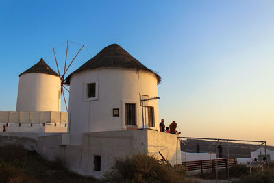 People by building against clear sky during sunset