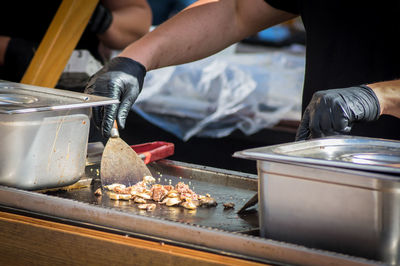 Midsection of chef preparing meat using spatula in kitchen at restaurant