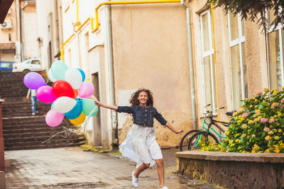 Full length of woman holding colorful balloons