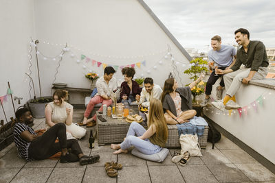 Group of multiracial friends having fun while celebrating during party in decorated balcony