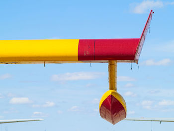 Low angle view of yellow and red structure against blue sky
