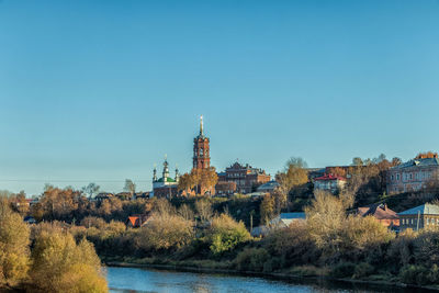 Panoramic view of buildings and trees against clear blue sky