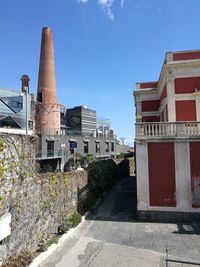 Street amidst buildings against blue sky