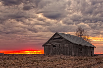 House on field against sky during sunset