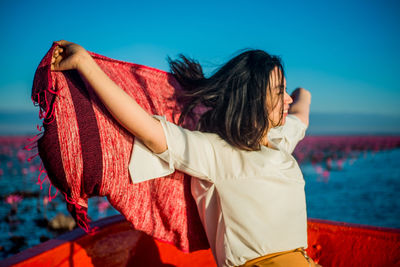 Rear view of women standing on beach against clear sky
