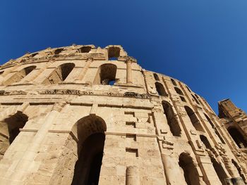 Low angle view of old ruin building against blue sky