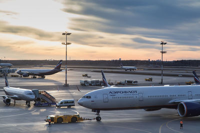 Airplane on airport runway against sky during sunset