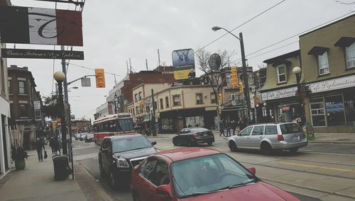 Cars on city street against sky