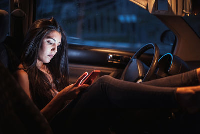 Young woman using smart phone while sitting in car