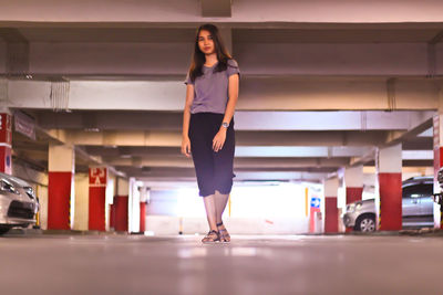 Full length portrait of woman standing in corridor