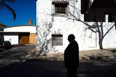 Rear view of man walking on street against buildings in city