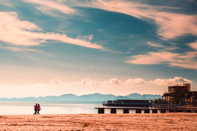 Man standing on beach against sky during sunset