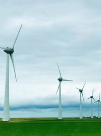 Wind turbines on field against sky