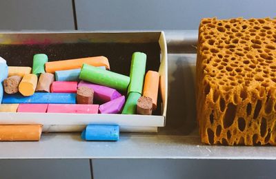 Close-up of multi colored chalks and sponge on table