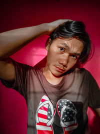 Portrait of young woman standing against wall