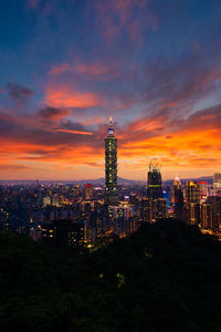 Illuminated city against sky during sunset