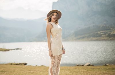 Young woman standing by sea against sky