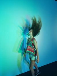 Full length of young woman standing against blue background