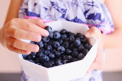 Midsection of woman holding blueberries in container