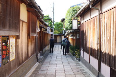 Rear view of people walking on footpath amidst buildings