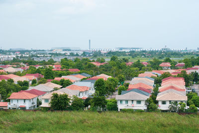 Houses on field by buildings against sky