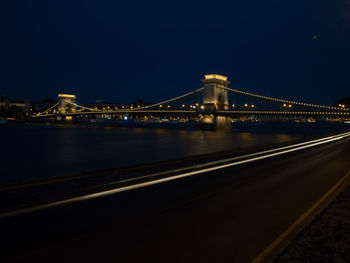 Illuminated bridge over river at night