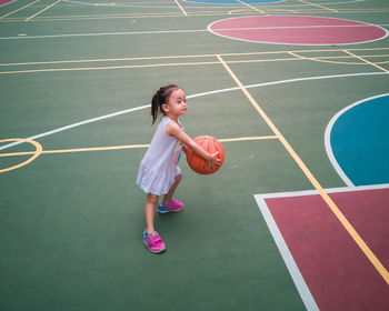 Full length of girl playing with basketball