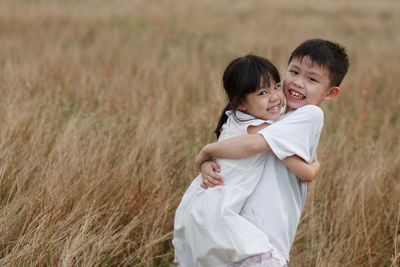 Portrait siblings embracing on grassy field