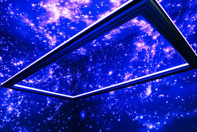 Low angle view of illuminated window against sky at night