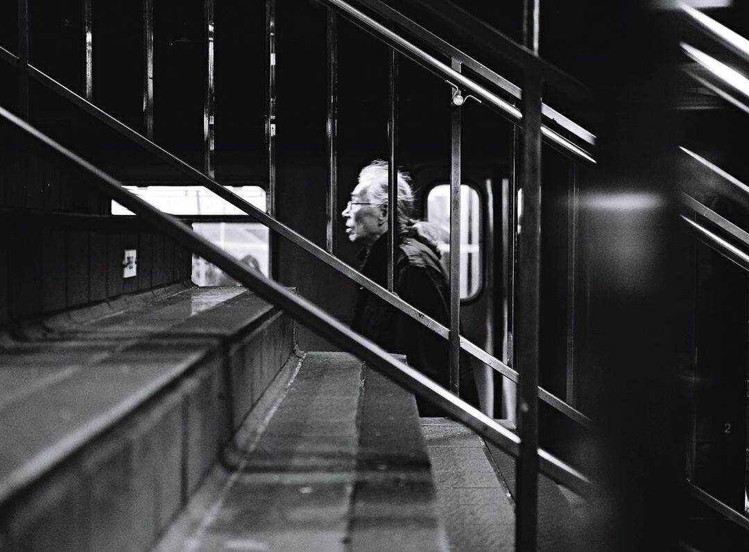 LOW ANGLE VIEW OF WOMAN WALKING UP STAIRS IN ILLUMINATED STAIRCASE