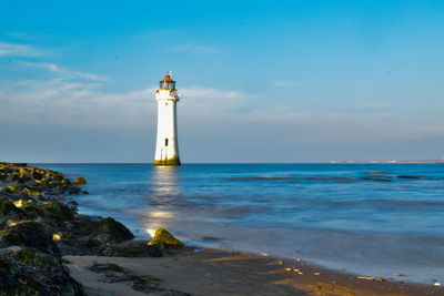 Lighthouse by sea against sky