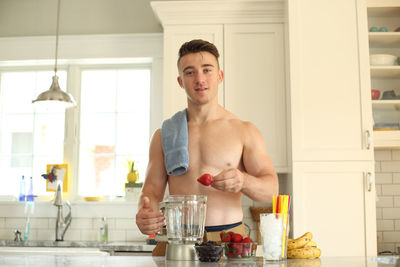 Portrait of shirtless man holding food at home