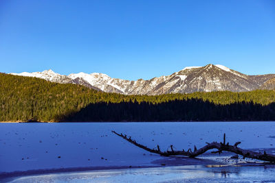 Scenic view of lake and mountains against clear blue sky