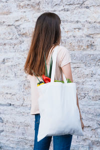 Young happy woman hold grocery tote shopping bag full of fresh vegetables.