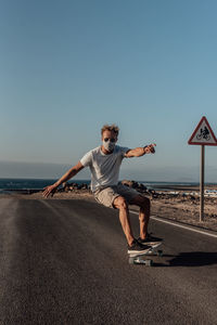 Full length of man on electric skateboard  against clear sky