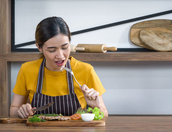 Young woman looking away while sitting on table