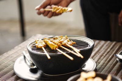 Close-up of person preparing food on barbecue grill