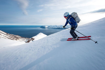 A man skiing downhill with ocean in the background in iceland
