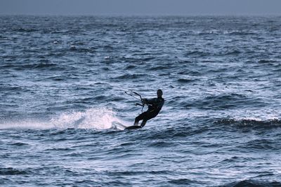 Full length of person kiteboarding in sea against sky