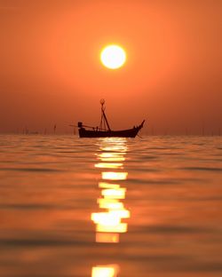 Silhouette person in sea against sky during sunset