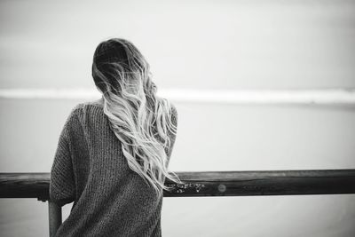 Rear view of woman standing by railing against sea