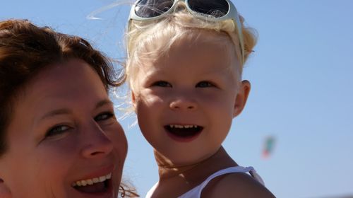 Portrait of happy mother and daughter against sky