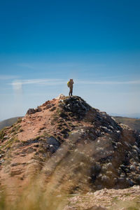 Man standing on rock against sky