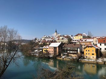 Town by river against clear sky